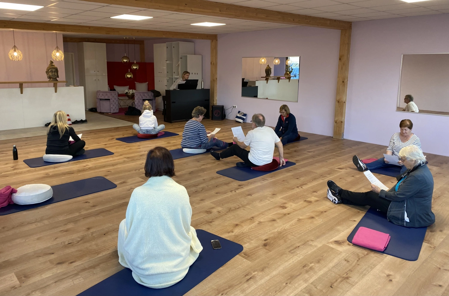 Menschen sitzen auf Yogamatten im Studio