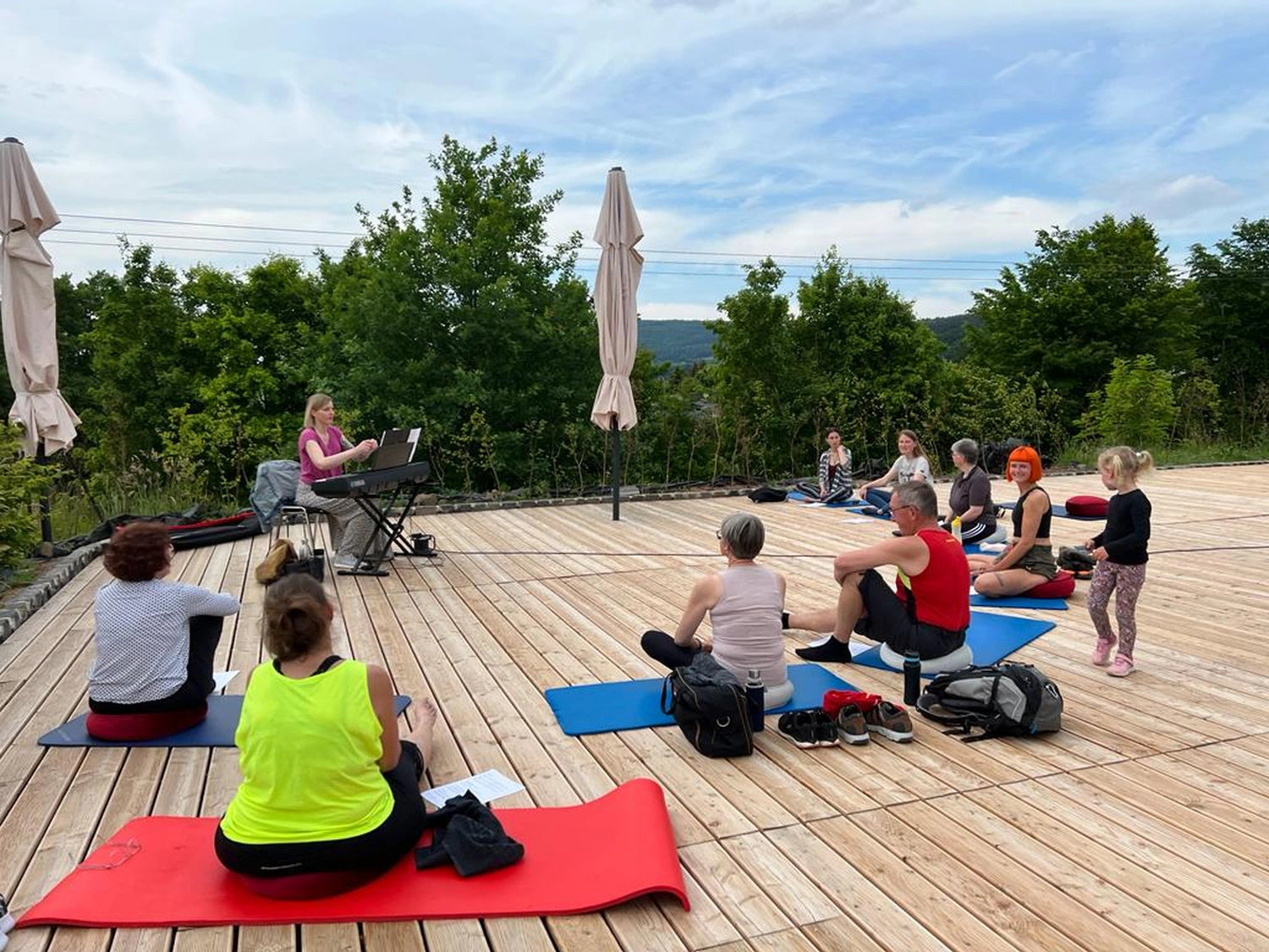 Menschen sitzen im Freien auf Yogamatten