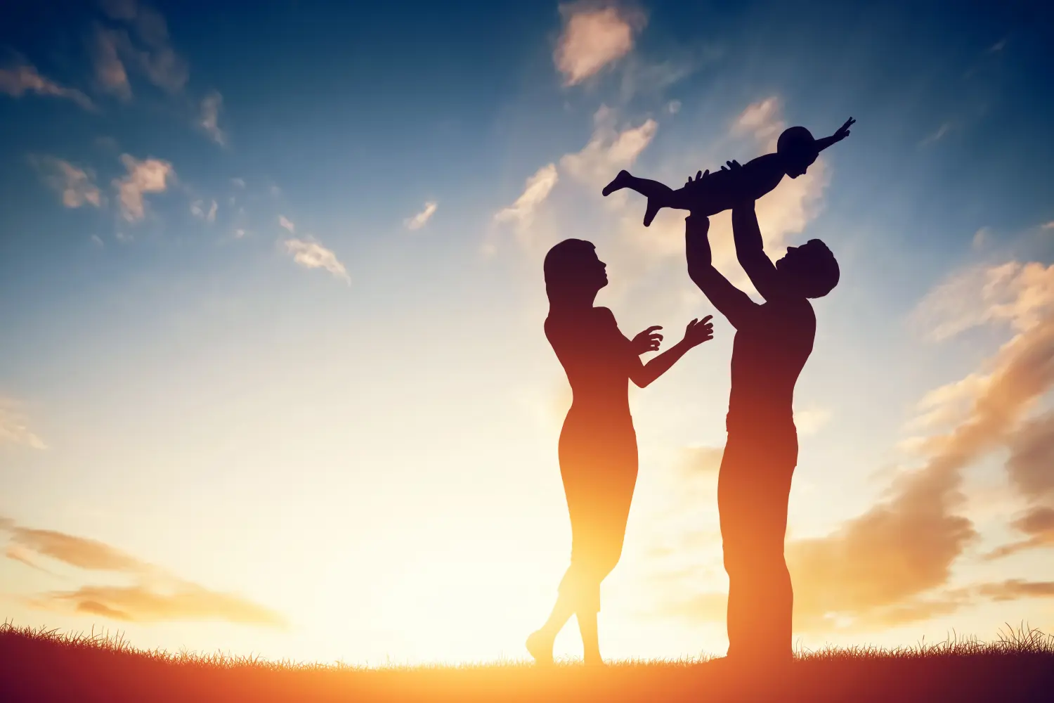 Eltern mit ihrem kleinen Baby bei Sonnenuntergang